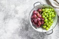 A branch of red and green grapes in a colander. Gray background. Top view. Copy space Royalty Free Stock Photo