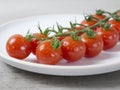 branch of red small tomatoes on white plat