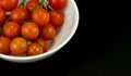 Branch of ripe cherry tomatoes on plate, top view in the black background. Close up photo Royalty Free Stock Photo