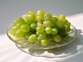 Branch of ripe green grape on a glass plate. Juicy lush grapes over white background, closeup shot