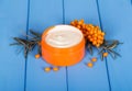 A branch with ripe sea-buckthorn berries and jar of cream on the Royalty Free Stock Photo