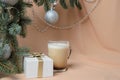 Branches of a Christmas tree, decorated with silver balls, a gift box, a glass mug with coffee and milk Royalty Free Stock Photo