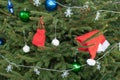 on the branches of the Christmas tree hangs a garland, a Santa Claus hat, toys and a red bag with a gift Royalty Free Stock Photo