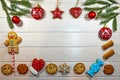 Branches of a Christmas tree, New Year`s decor, gingerbread and cookies on a light wooden background. Macro, horizontal photo.