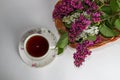 Branches of lilac and white lilac in a wicker basket and a cup of black tea with lilac flowers isolated on a white background Royalty Free Stock Photo