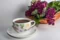 Branches of lilac and white lilac in a wicker basket and a cup of black tea with lilac flowers isolated on a white background Royalty Free Stock Photo