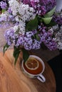 Branches of lilac and white lilac in a wicker basket and a cup of black tea with lilac flowers isolated on a white background Royalty Free Stock Photo