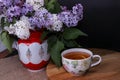 Branches of lilac and white lilac in a wicker basket and a cup of black tea with lilac flowers isolated on a white background Royalty Free Stock Photo