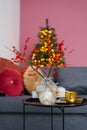 Branches with red berries in a glass vase are on the coffee table in the living room, decorated for Christmas Royalty Free Stock Photo