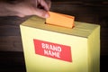 Brand Name. Yellow ballot box on a wooden background. Survey and evaluation