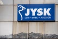 Brand sign of Danish furniture giant Jysk on the glass facade with reflection of the mountains below it