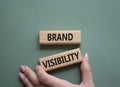 Brand visibility symbol. Wooden blocks with words Brand visibility. Beautiful grey green background. Businessman hand. Business