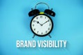Brand Visibility text and alarm clock on blue background Royalty Free Stock Photo