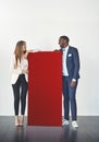 Branding for your business needs. Studio shot of a young businessman and businesswoman standing next to a blank red Royalty Free Stock Photo