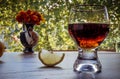 Brandy or cognac in the glass with lemon on table. Orange flowers in vase. ture.