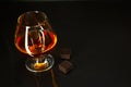 Brandy glass and chocolate on black background Royalty Free Stock Photo