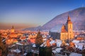 Brasov, Romania. Winter snowy downtown, sunset time, Black Church and Carpathian Mountains