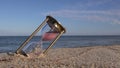 Brass ancient hourglass sandglass clock on sea beach sand