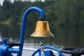 Brass bell on the foredeck of a ship against the background of a blurred wooded coast
