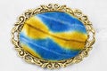 Brass brooch with hand-colored silk batik on gray Royalty Free Stock Photo