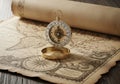 A brass compass sits on a rolled, vintage-style map displaying intricate geographical details. The Royalty Free Stock Photo