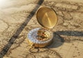 A brass compass with a slightly open lid rests on an old world map featuring continents and seas. Royalty Free Stock Photo