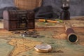 Brass compass and a spyglass lie on an old map against the background of a forged chest with coins. Royalty Free Stock Photo