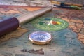 Brass compass, a spyglass, a pencil with a compass and multi-colored markers lie on an old map.