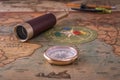 Brass compass, a spyglass, a pencil with a compass and multi-colored markers lie on an old map.