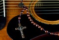 Crucifix and Rosary Beads on a Mahogany Acoustic Guitar Royalty Free Stock Photo