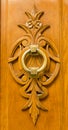 Brass door knocker on a wooden carving Royalty Free Stock Photo