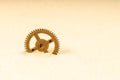 Brass gear in yellow sand, gear sticking out of the sand Royalty Free Stock Photo