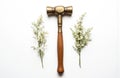Brass hammer with gold handle on white background. Delicate white flowers with stems add elegance. Harmonious composition Royalty Free Stock Photo