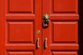 Brass lion head door knocker at the red wooden door. Royalty Free Stock Photo