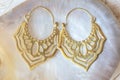 Brass metal earrings on white shell natural background