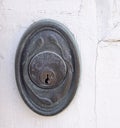 Brass metal keyhole plate with light aqua patina on white painted background