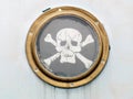 Brass porthole on ship with pirate flag Royalty Free Stock Photo