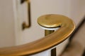 Brass volute newel at bottom of staircase against white