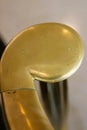 Brass volute newel at bottom of staircase against white, vertical