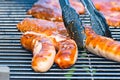 Brat sausage is served on the charcoal grill with the grill tongs