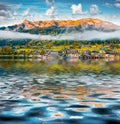 Brauhof village reflected in calm waters of Grundlsee lake.