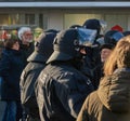 Police officers with helmets with visor and neck guard in black uniforms between elderly people demonstrating