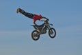 A brave biker jumps very high on a motorcycle and performs a stunt.