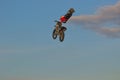 A brave biker jumps very high on a motorcycle and performs a stunt.