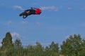 A brave biker jumps very high on a motorcycle and performs a stunt.