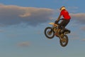 A brave biker jumps very high on a motorcycle and performs a stunt.