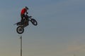 A brave biker jumps very high on a motorcycle and performs a stunt.