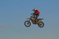 A brave biker jumps very high on a motorcycle and performs a stunt.