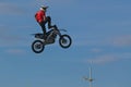 A brave biker jumps very high on a motorcycle and performs a stunt.