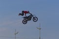 A brave biker jumps very high on a motorcycle and performs a stunt.